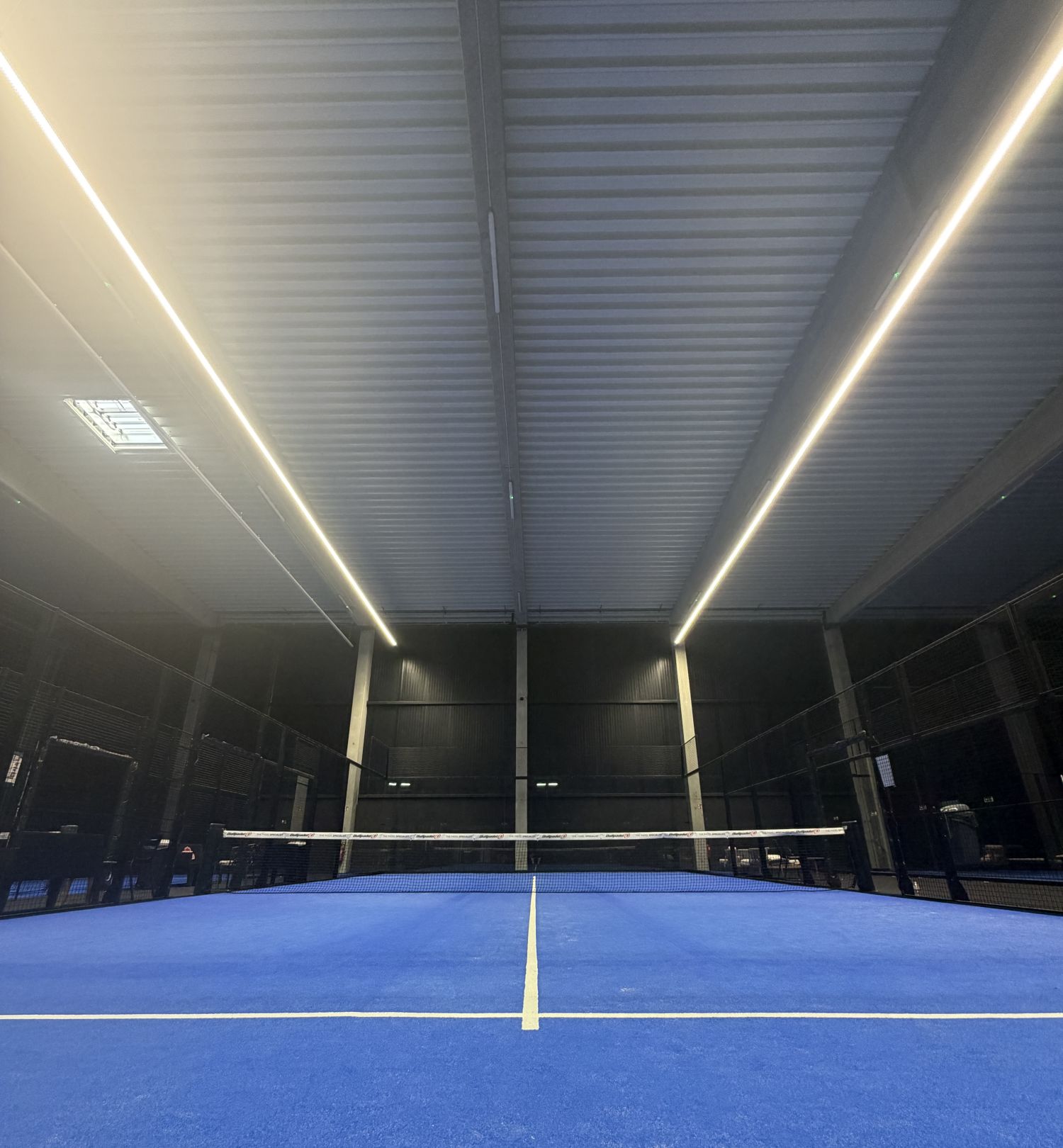 Les bandeaux LED continus qui éclairent un terrain intérieur d'Athois Le Padel